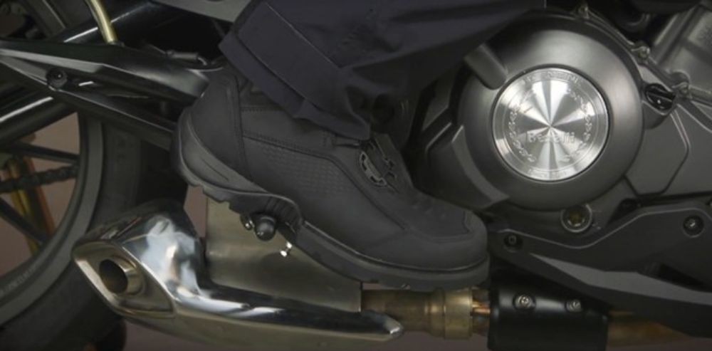 Close-up of Icon Stormhawk WP motorcycle shoes on footpeg, showing rugged build and waterproof design