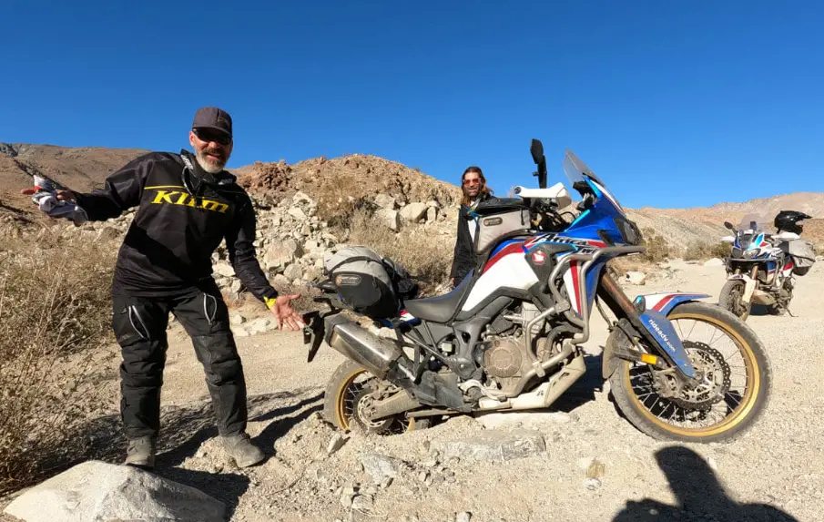 adventure rider fixing their bike in the desert