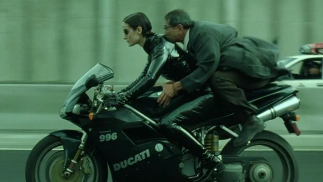 TRINITY RIDING MOTORCYCLE IN THAT SICK LEATHER SUIT